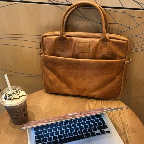 14″ Brown Leather Laptop Bag on round table with a frappachino and an apple macbook.